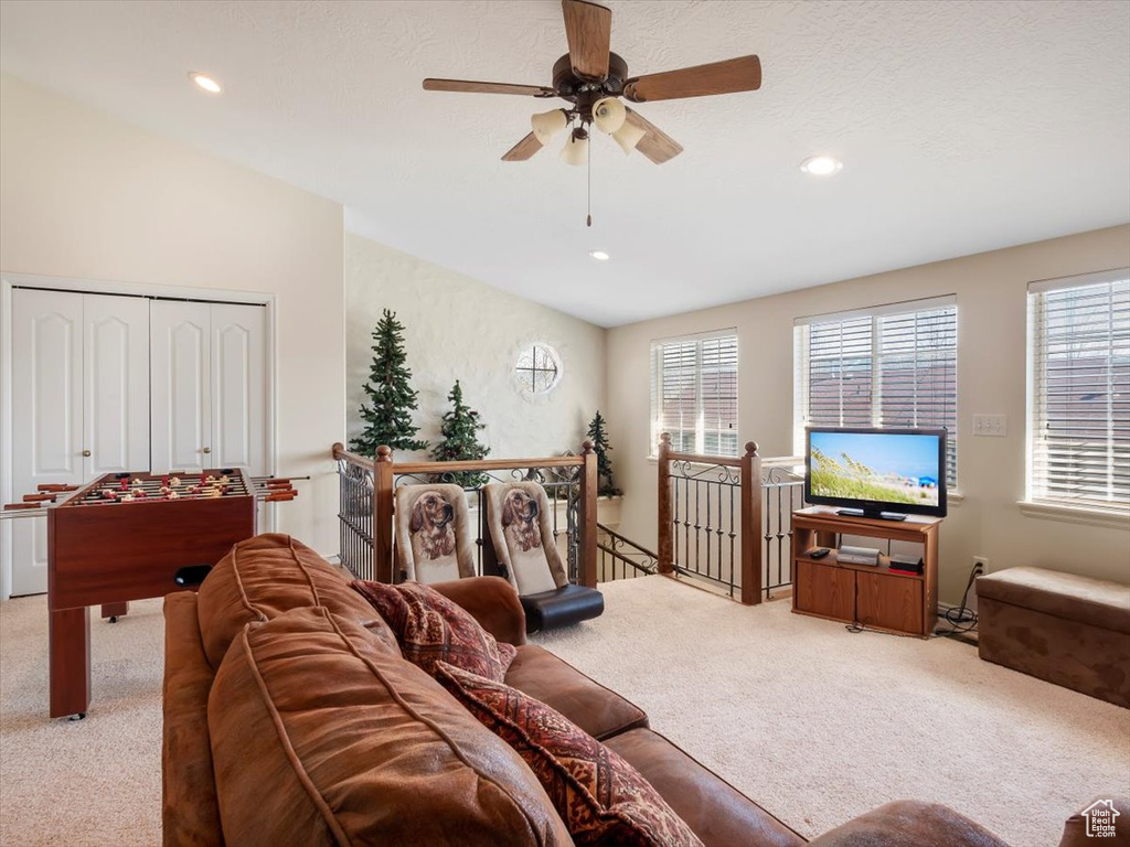 Carpeted living room featuring ceiling fan, plenty of natural light, and vaulted ceiling