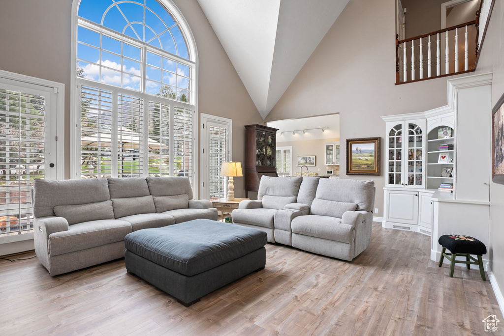 Living room with high vaulted ceiling and light hardwood / wood-style flooring