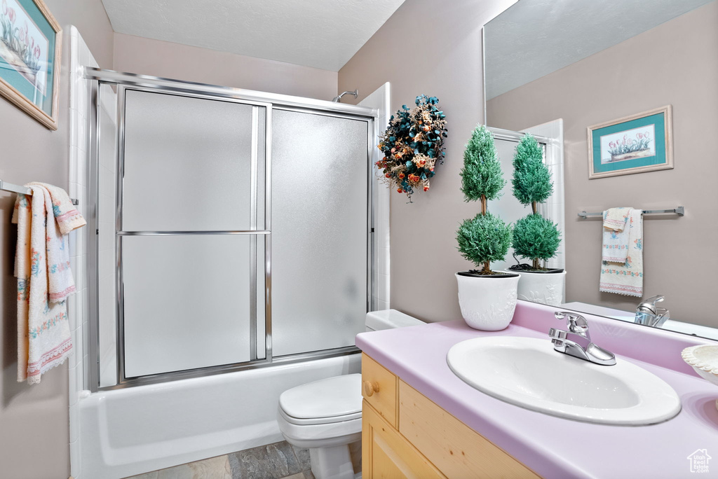 Full bathroom with tile floors, vanity, toilet, and shower / bath combination with glass door