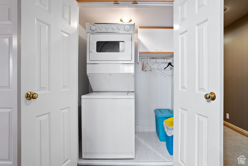 Laundry area featuring light colored carpet and stacked washer and clothes dryer