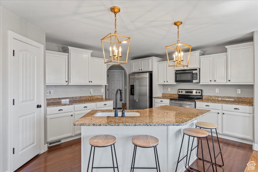 Kitchen featuring appliances with stainless steel finishes, hanging light fixtures, dark hardwood / wood-style floors, and sink