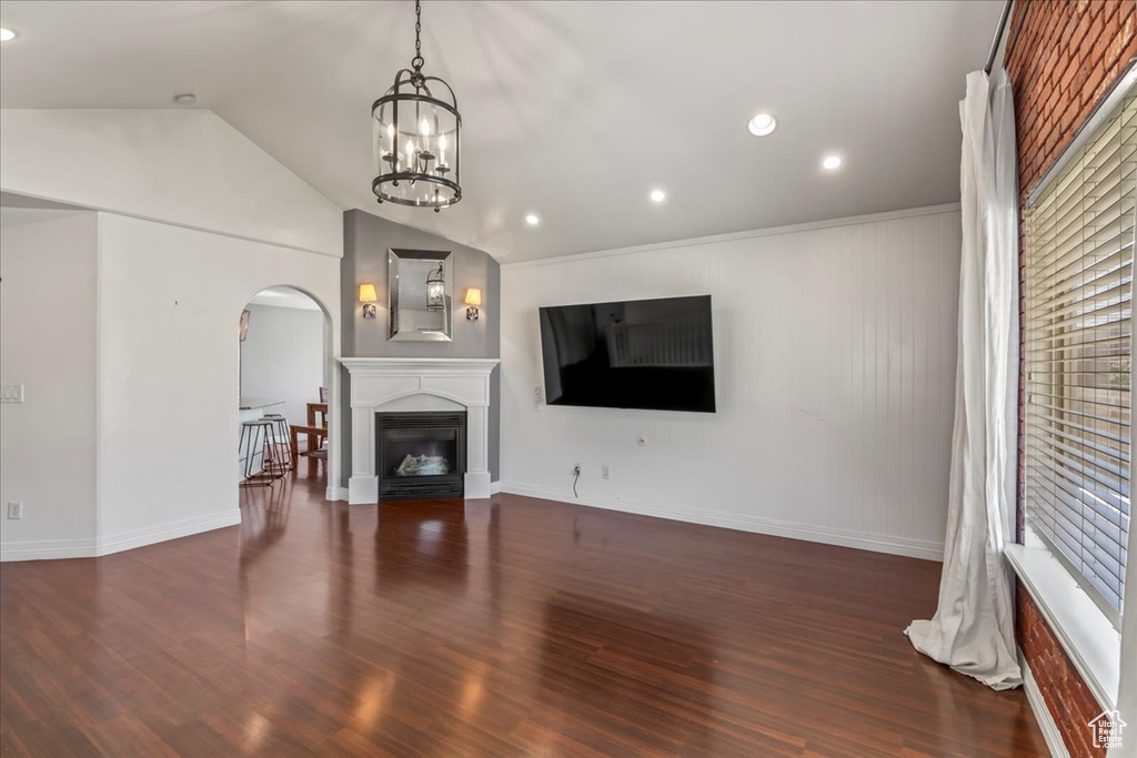 Unfurnished living room with dark hardwood / wood-style flooring, a chandelier, and vaulted ceiling