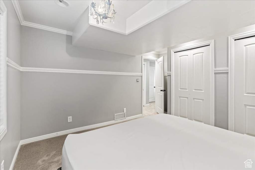 Bedroom with carpet flooring, an inviting chandelier, crown molding, and a closet