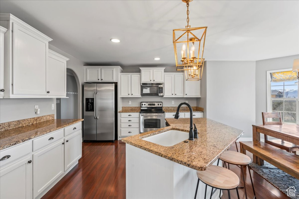 Kitchen featuring hanging light fixtures, appliances with stainless steel finishes, white cabinetry, and dark wood-type flooring