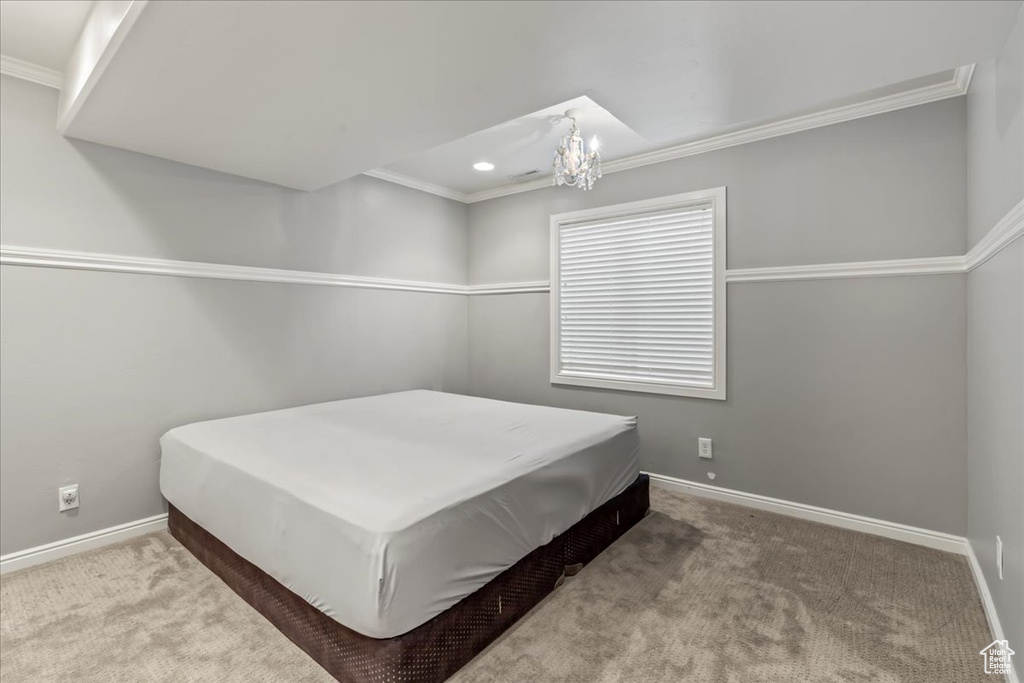 Carpeted bedroom with a notable chandelier and crown molding
