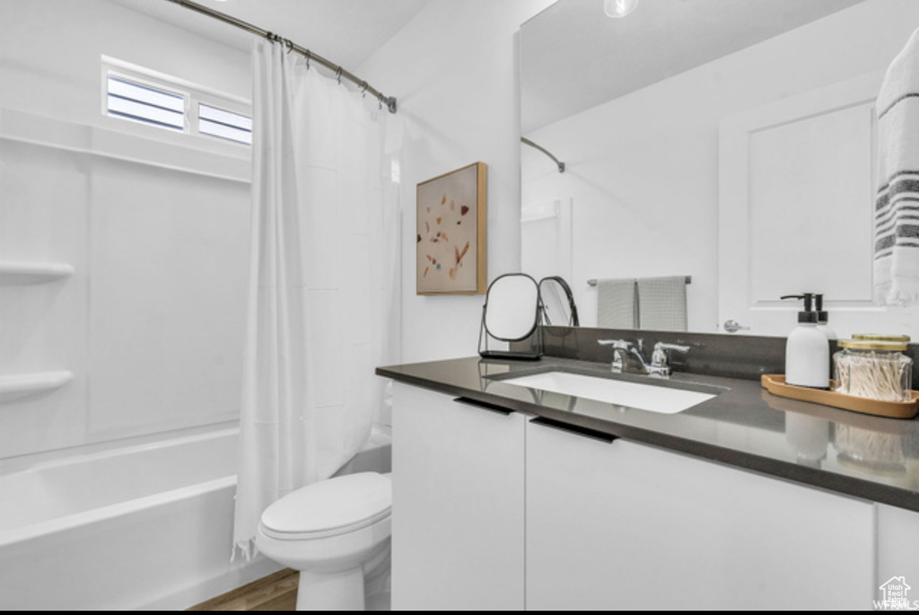Full bathroom with vanity, shower / bath combination with curtain, and toilet