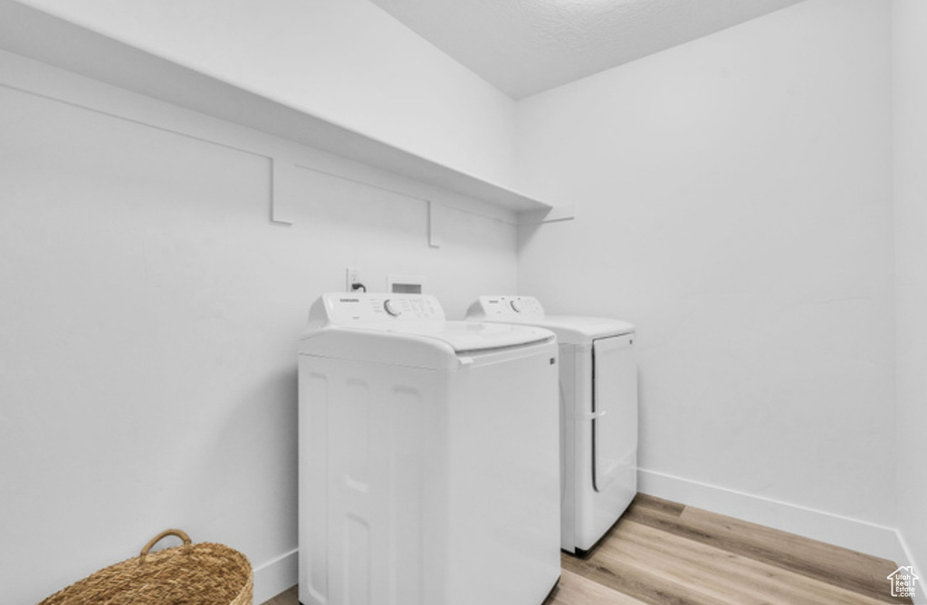 Clothes washing area featuring independent washer and dryer and light hardwood / wood-style flooring