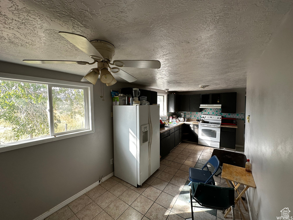 Kitchen featuring white appliances, light tile floors, tasteful backsplash, ceiling fan, and a textured ceiling