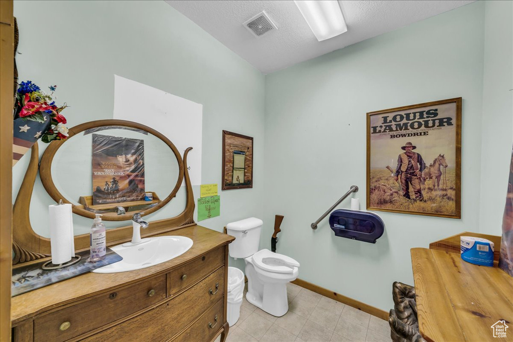 Bathroom featuring toilet, tile flooring, vanity, and a textured ceiling
