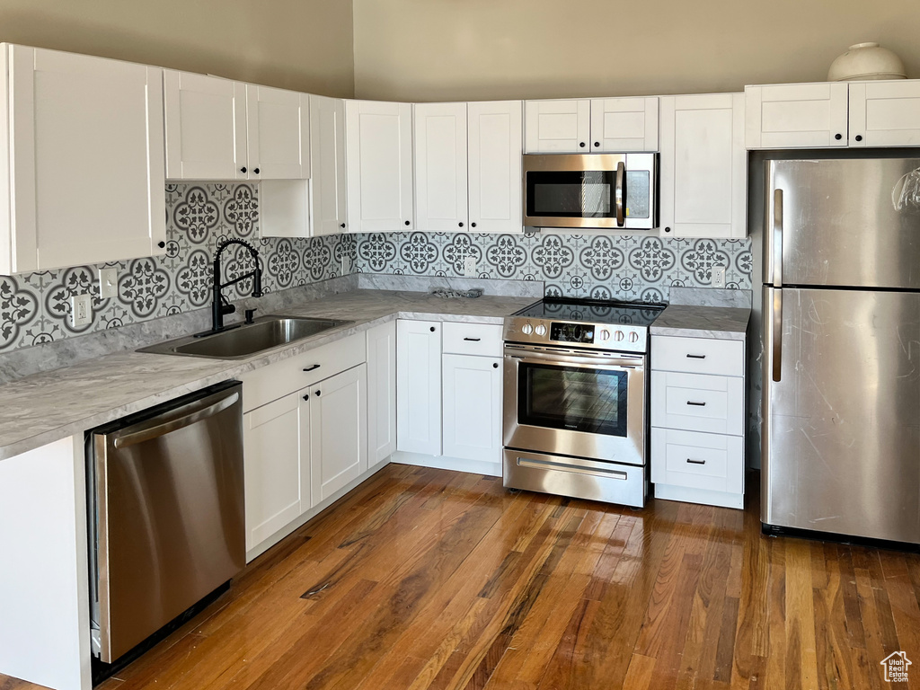 Kitchen featuring white cabinetry, stainless steel appliances, dark hardwood / wood-style floors, and sink