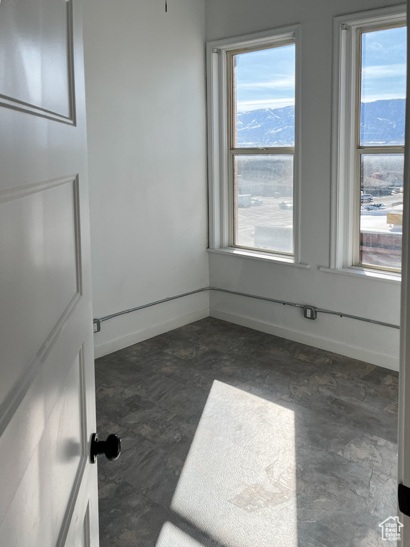 Tiled empty room featuring a mountain view and a healthy amount of sunlight