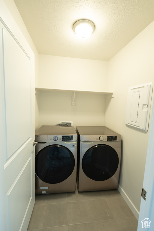 Clothes washing area with light tile flooring, washer and dryer, and hookup for a washing machine