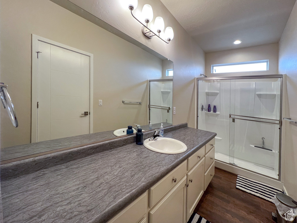 Bathroom featuring hardwood / wood-style floors, oversized vanity, and a shower with door