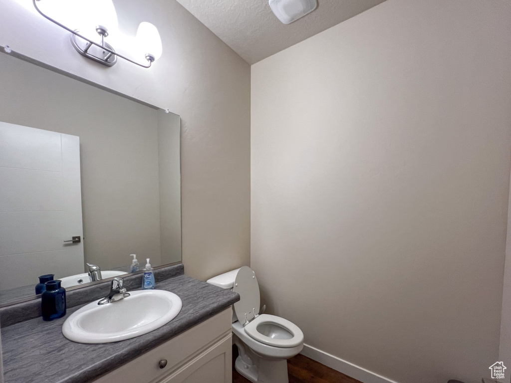 Bathroom featuring toilet, hardwood / wood-style floors, vanity, and a textured ceiling