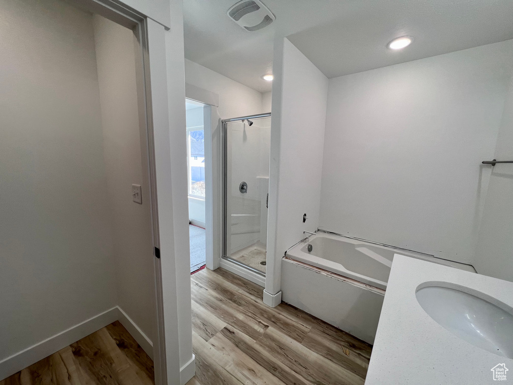 Bathroom with sink, independent shower and bath, and hardwood / wood-style floors
