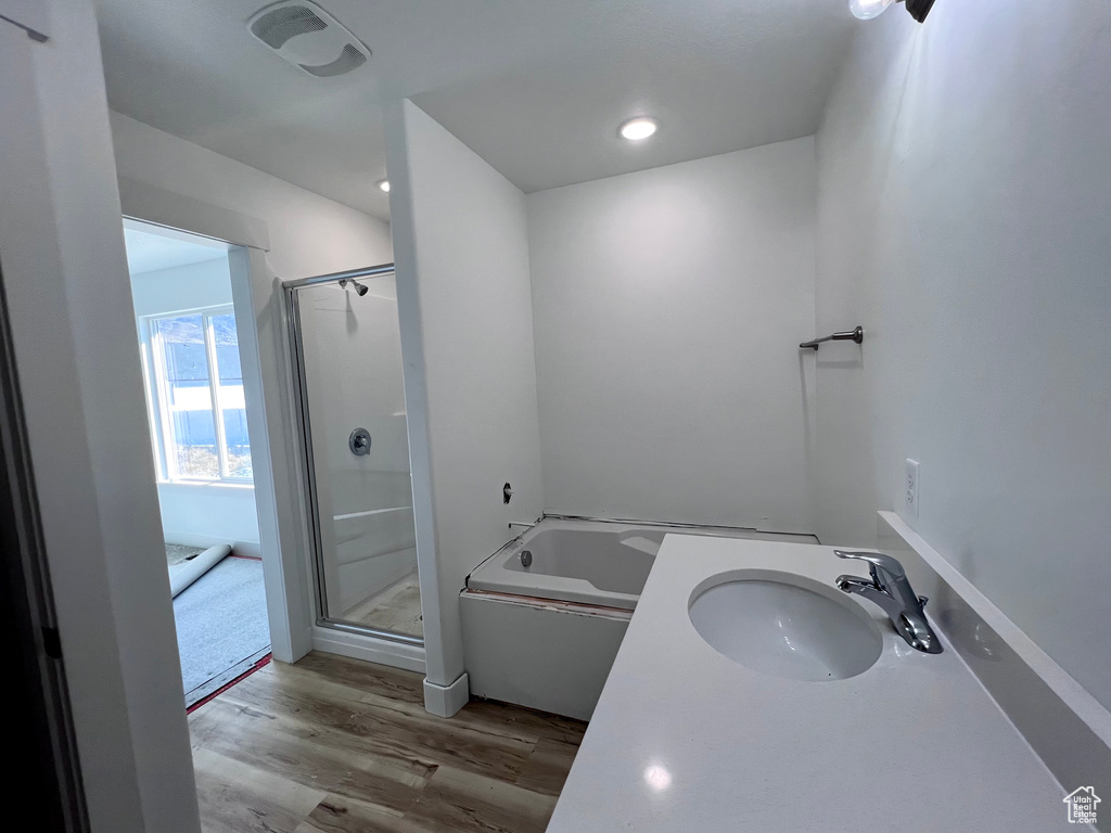Bathroom with wood-type flooring, vanity, and shower with separate bathtub