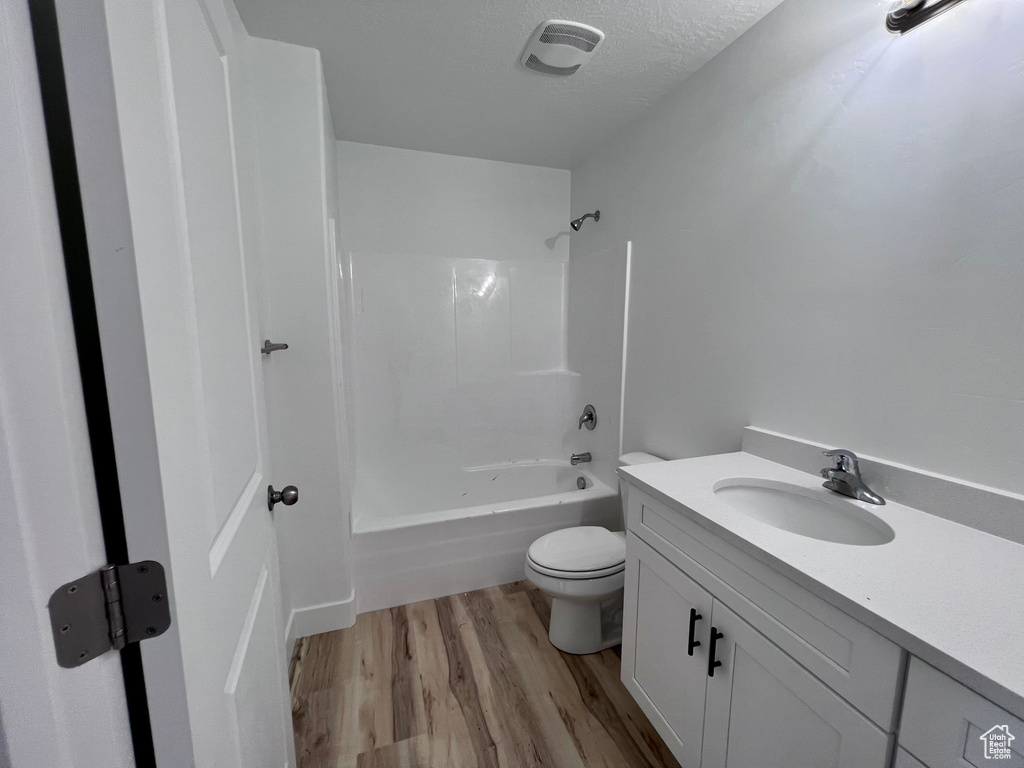 Full bathroom with shower / tub combination, vanity, hardwood / wood-style floors, toilet, and a textured ceiling