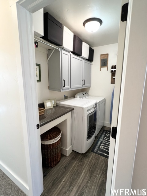 Clothes washing area with dark hardwood / wood-style flooring, cabinets, and separate washer and dryer