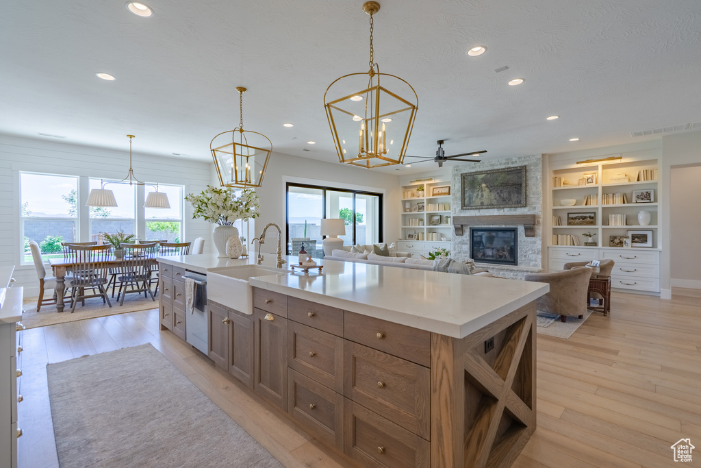 Kitchen featuring plenty of natural light, sink, light hardwood / wood-style floors, and a kitchen island with sink