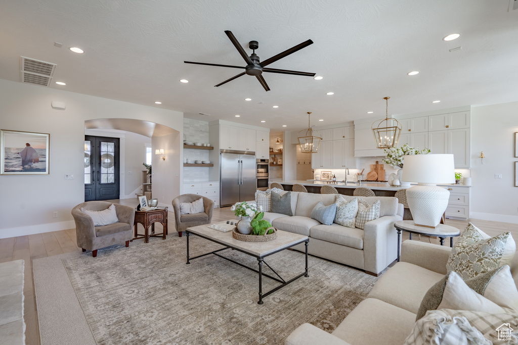 Living room featuring ceiling fan with notable chandelier, light hardwood / wood-style flooring, and sink