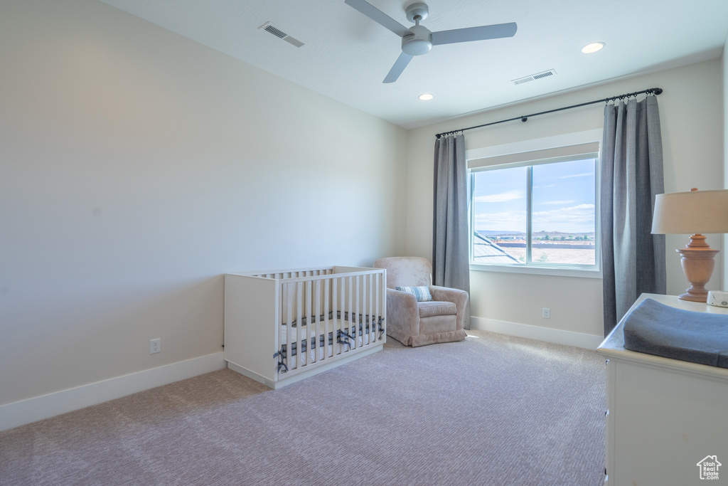 Unfurnished bedroom featuring carpet, ceiling fan, and a crib