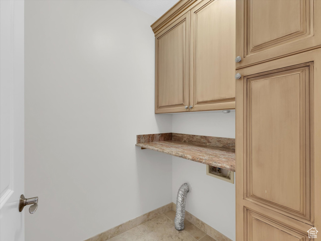 Clothes washing area with cabinets and light tile floors