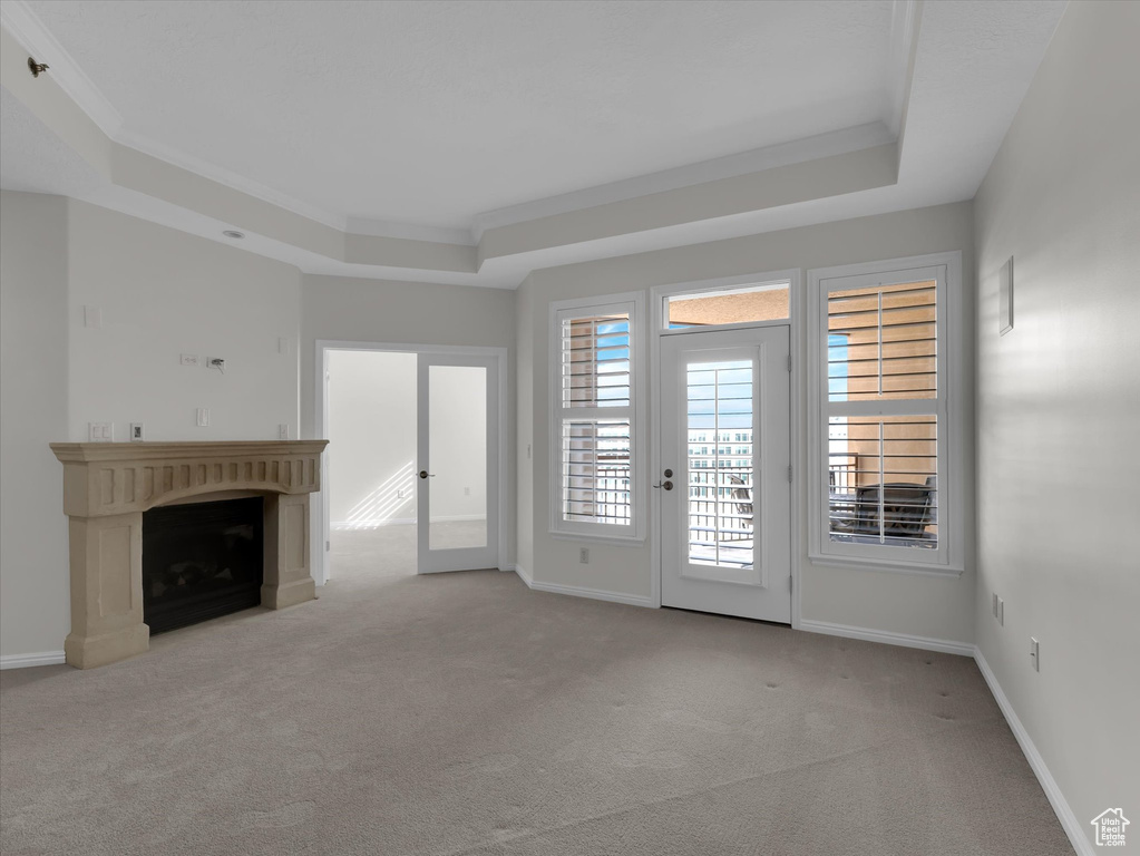 Unfurnished living room featuring french doors, crown molding, a raised ceiling, and carpet floors