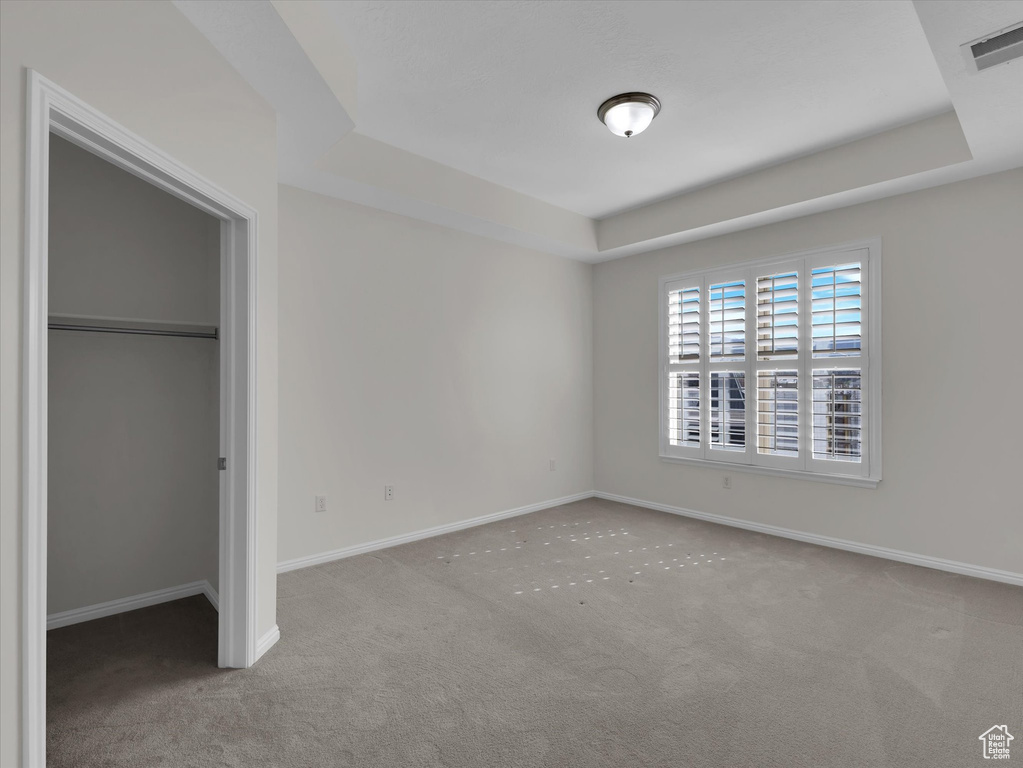 Unfurnished bedroom featuring a raised ceiling and carpet