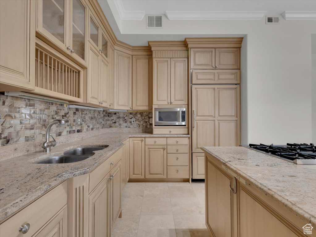Kitchen with stainless steel microwave, sink, ornamental molding, and backsplash