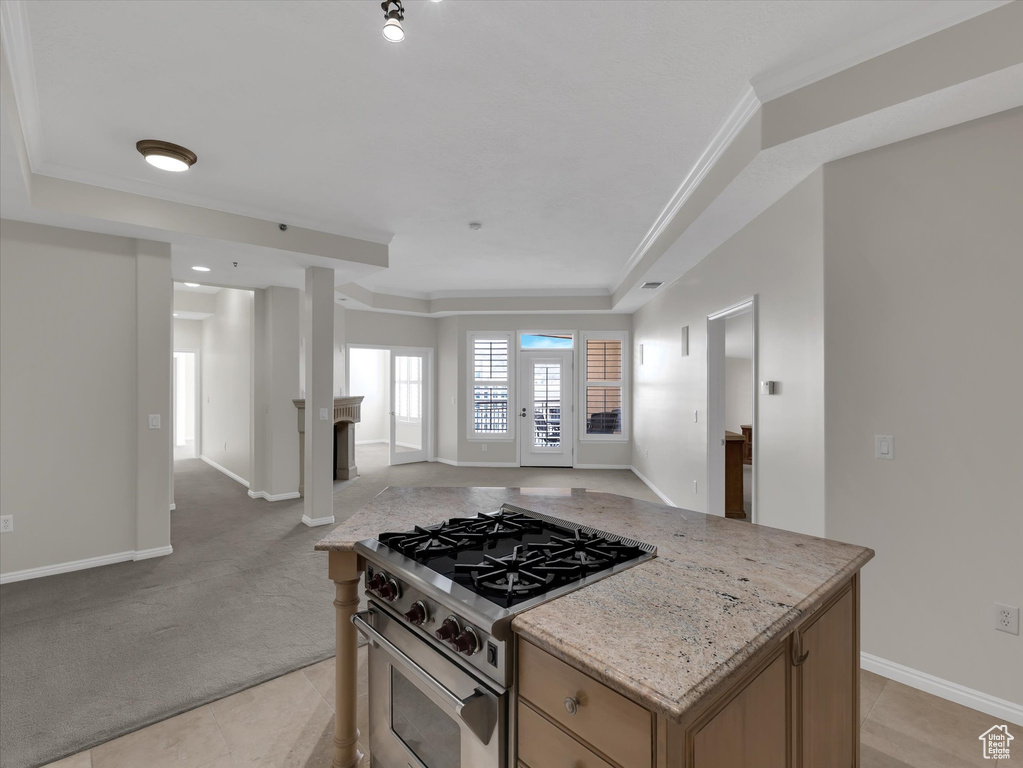 Kitchen featuring light colored carpet, light stone countertops, high end range, and ornamental molding