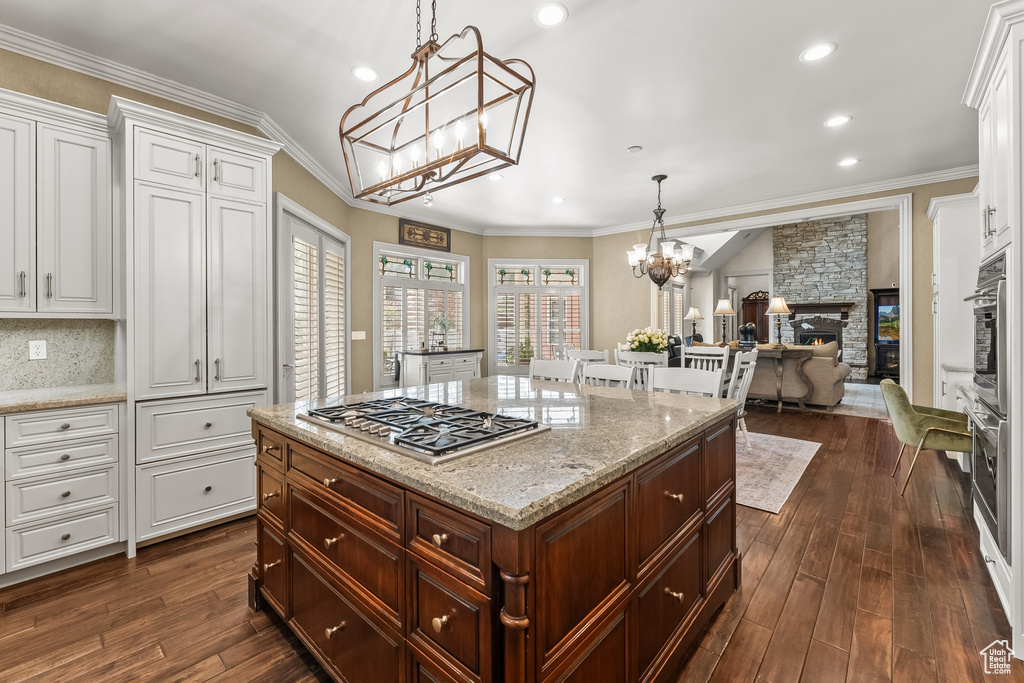 Kitchen with a stone fireplace, backsplash, appliances with stainless steel finishes, white cabinetry, and dark hardwood / wood-style flooring