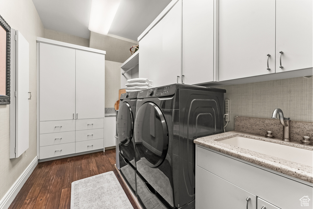 Clothes washing area featuring dark hardwood / wood-style floors, cabinets, sink, and washer and dryer