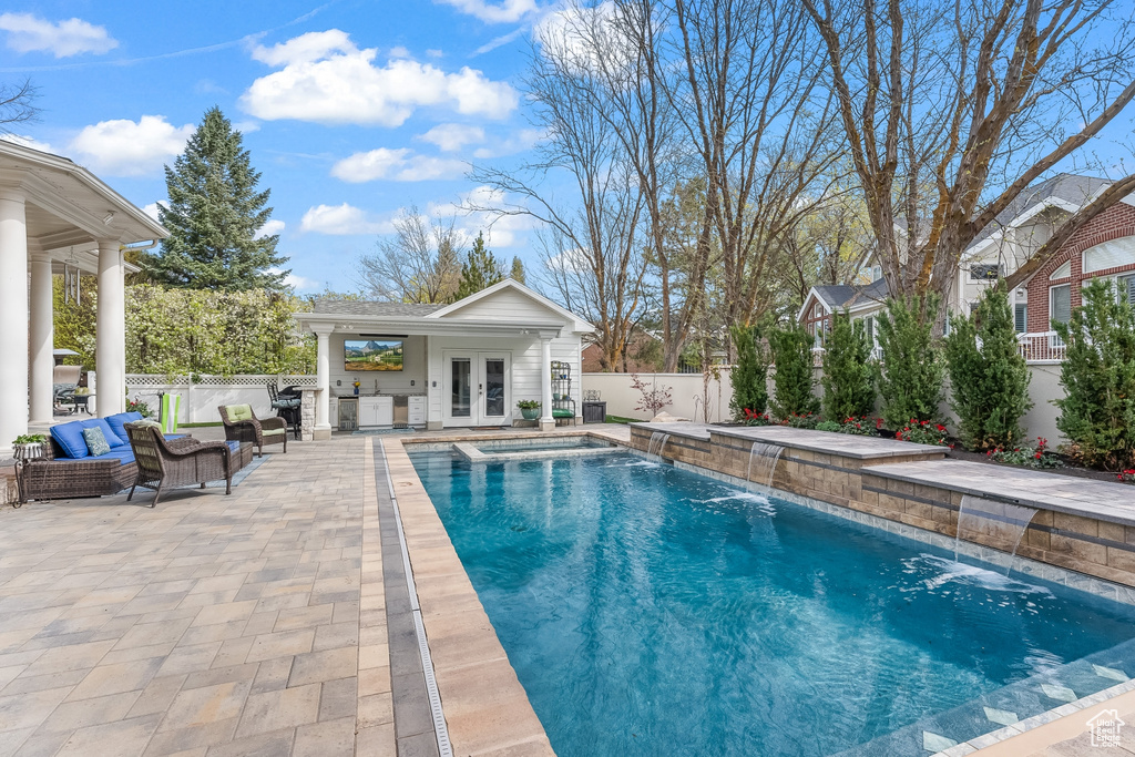 View of swimming pool with a patio, french doors, and pool water feature