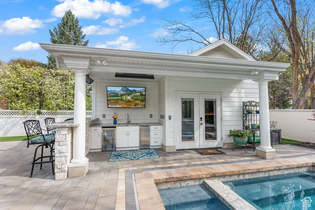 Exterior space featuring french doors, exterior kitchen, beverage cooler, and a wet bar