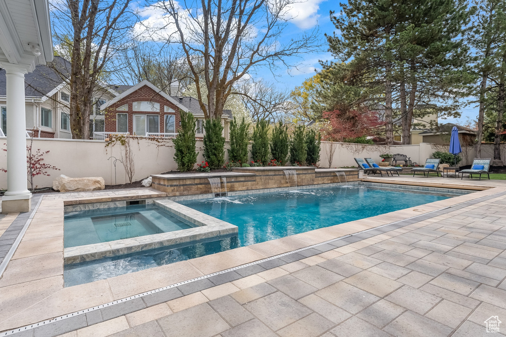 View of pool featuring a patio area, pool water feature, and an in ground hot tub
