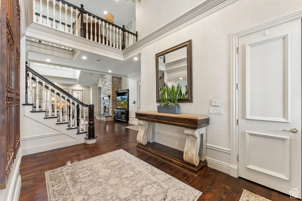 Foyer featuring a fireplace, dark hardwood / wood-style flooring, crown molding, and a high ceiling