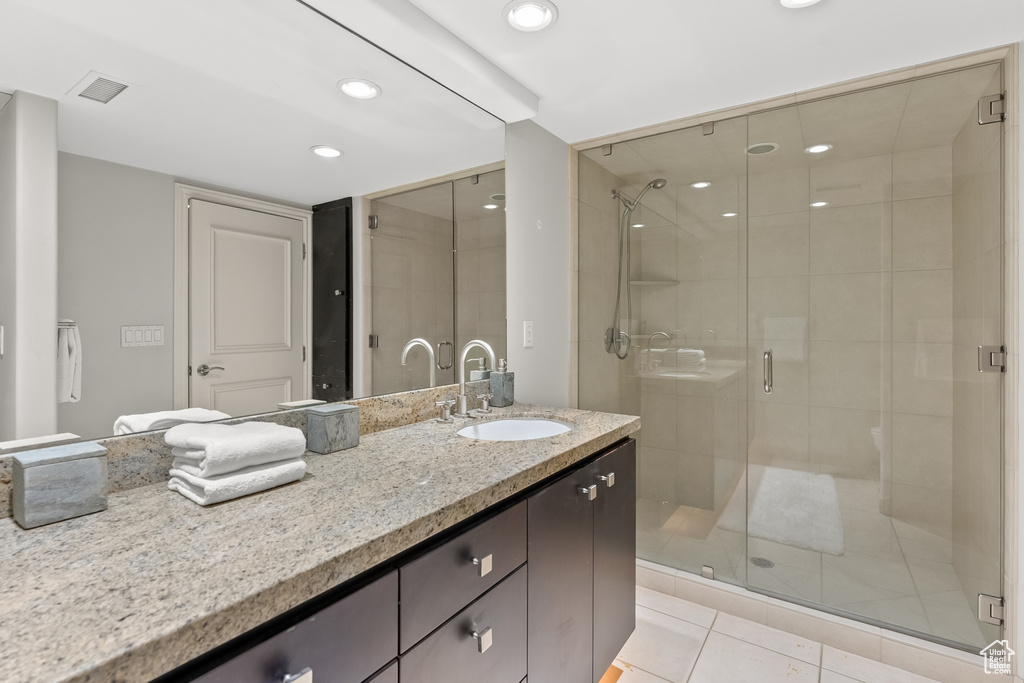 Bathroom featuring walk in shower, tile floors, and vanity with extensive cabinet space