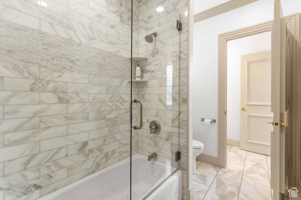 Bathroom with tile flooring, ornamental molding, toilet, and bath / shower combo with glass door