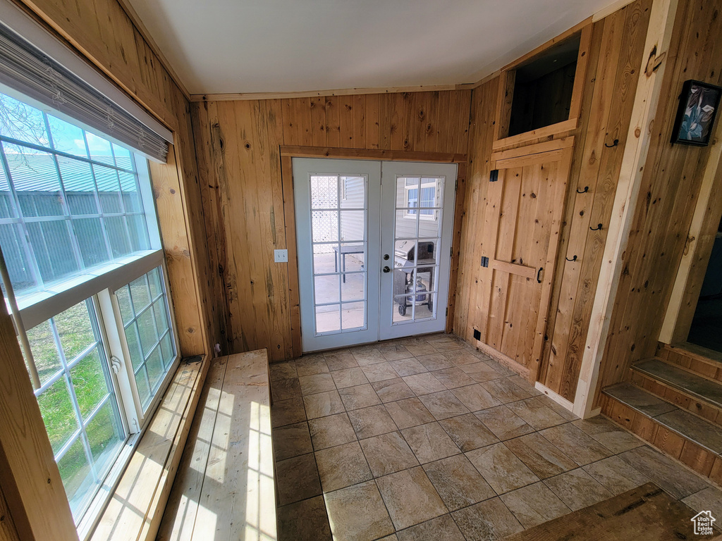 Doorway featuring tile flooring, plenty of natural light, french doors, and wooden walls