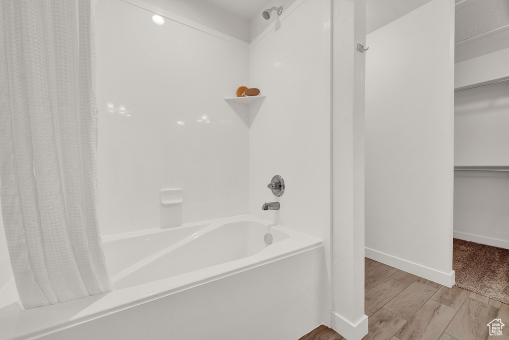 Bathroom with hardwood / wood-style flooring and shower / tub combo