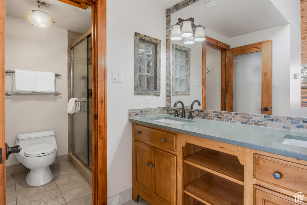 Bathroom with an enclosed shower, tile floors, dual vanity, tasteful backsplash, and toilet