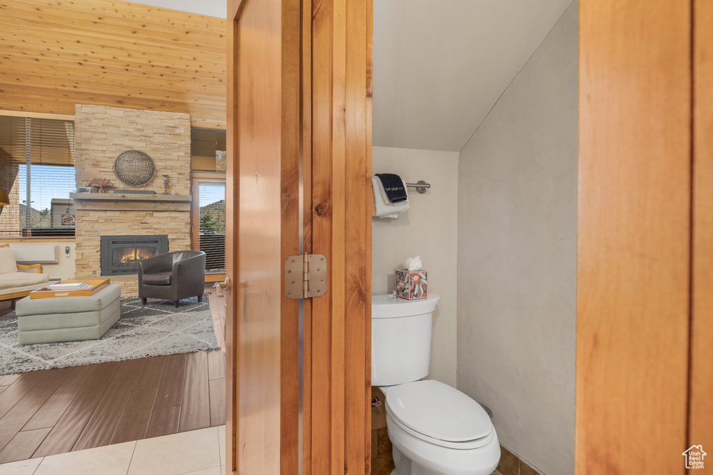 Bathroom with tile floors, wood walls, toilet, and a fireplace