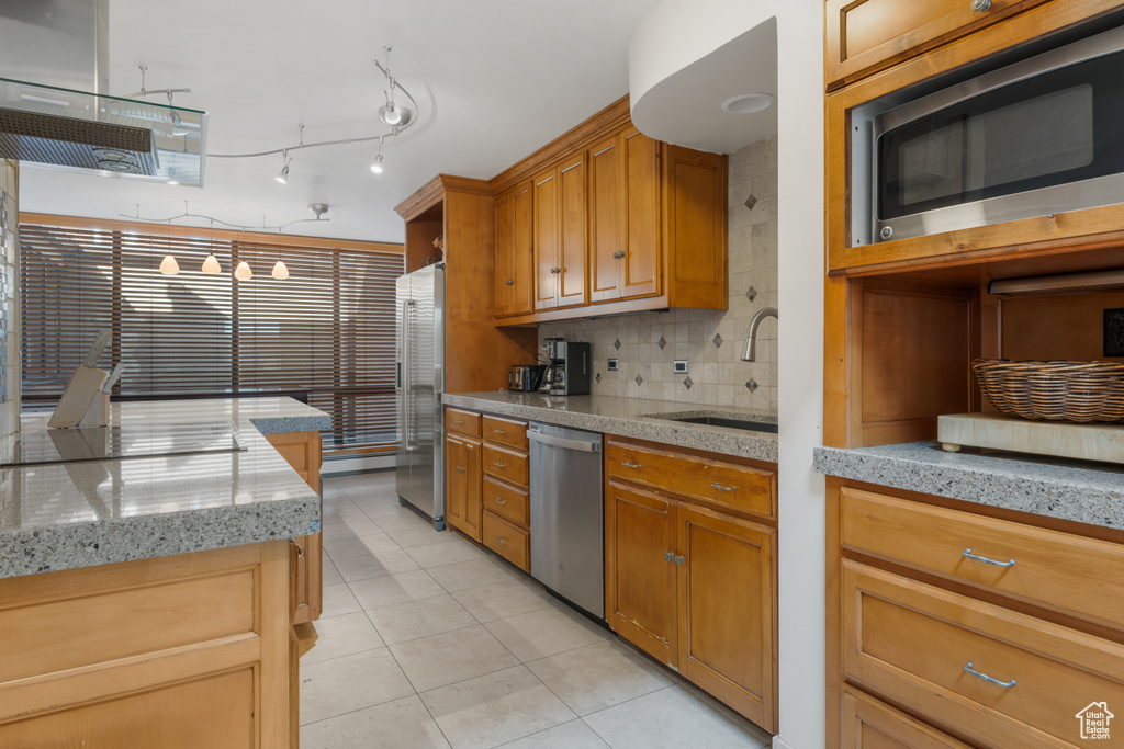 Kitchen with light tile flooring, rail lighting, backsplash, stainless steel appliances, and sink