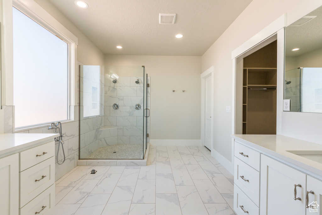 Bathroom featuring walk in shower, plenty of natural light, vanity, and tile floors