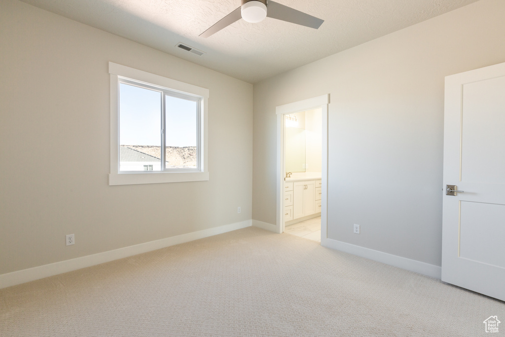 Unfurnished bedroom featuring light carpet, connected bathroom, and ceiling fan