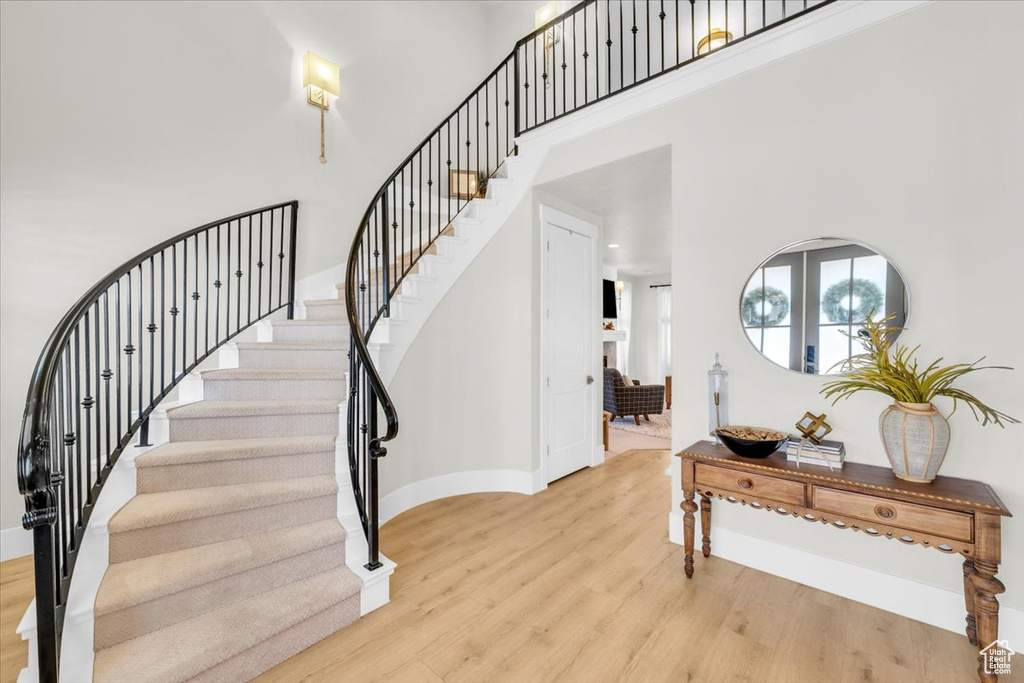 Stairway featuring french doors, a towering ceiling, and light wood-type flooring