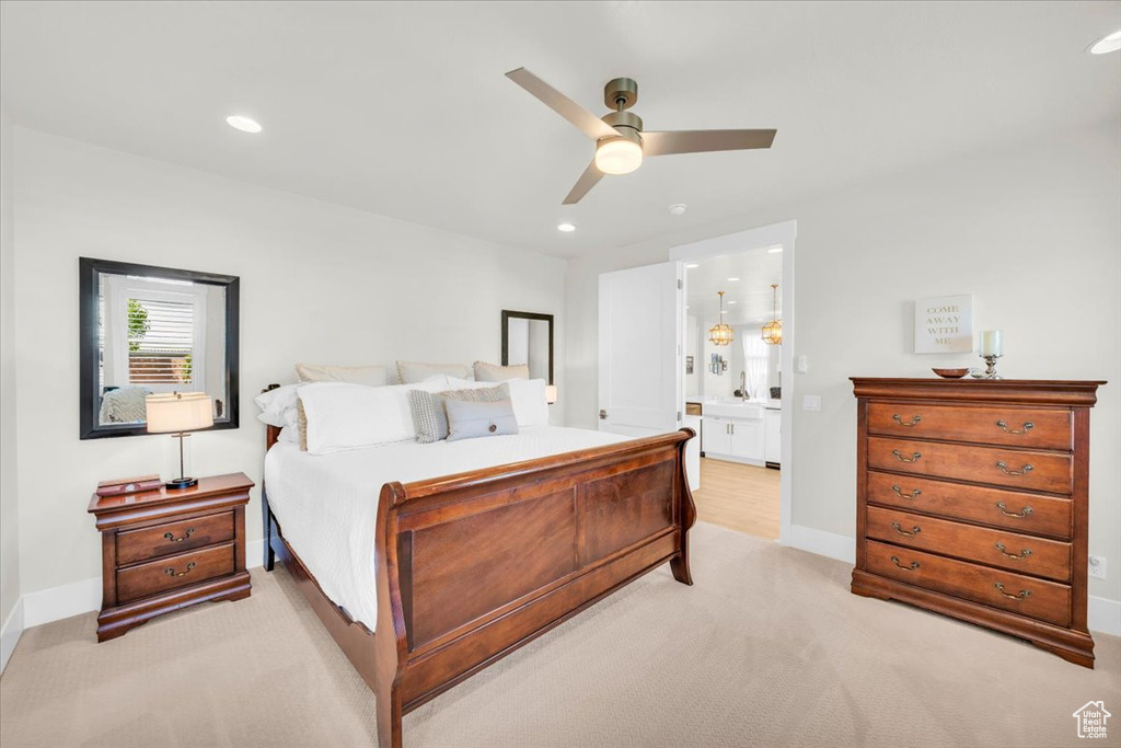Bedroom featuring light colored carpet, ceiling fan, and ensuite bathroom