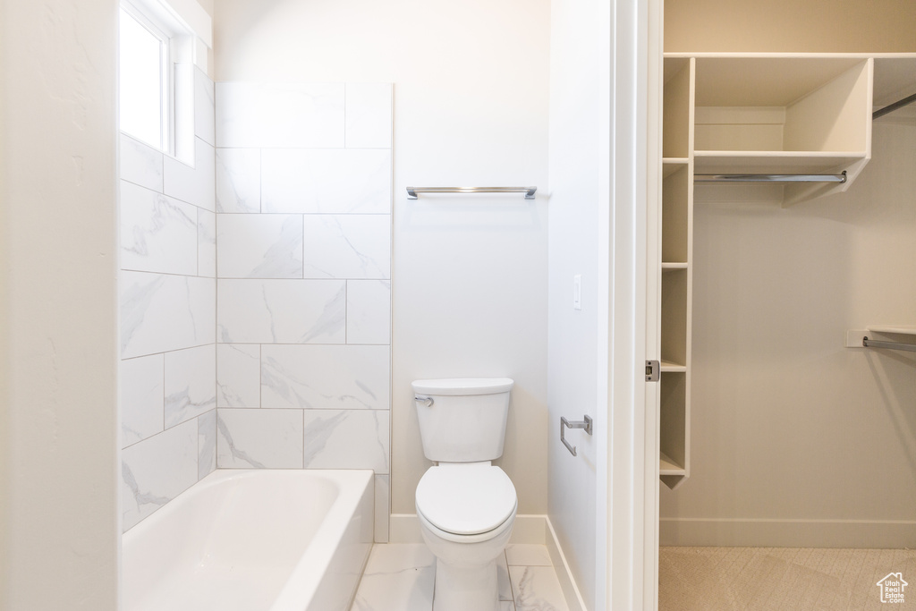 Bathroom featuring tiled shower / bath, toilet, and tile floors