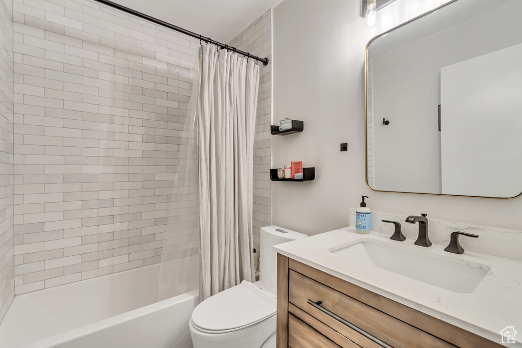 Full bathroom with toilet, vanity, and shower / tub combo with curtain
