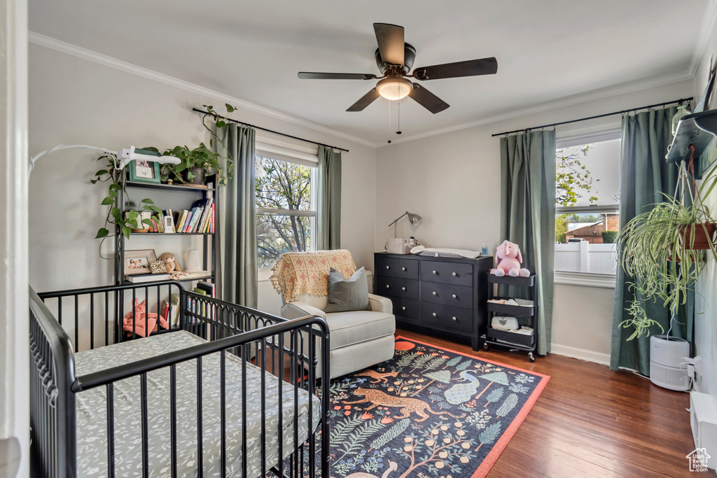 Bedroom featuring ornamental molding, wood-type flooring, a nursery area, and ceiling fan